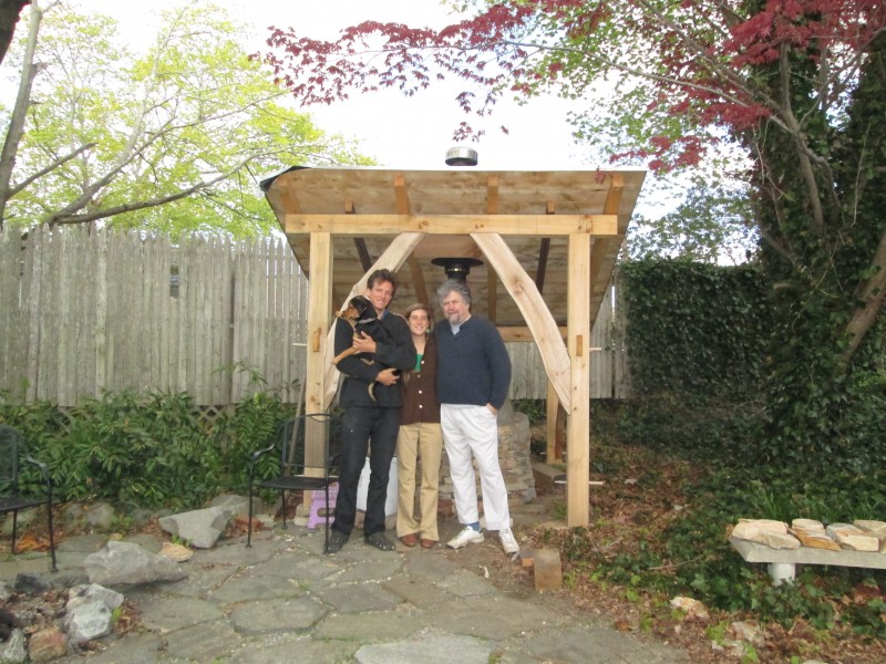 family in front of earth oven and timber frame shelter in Rhode Island