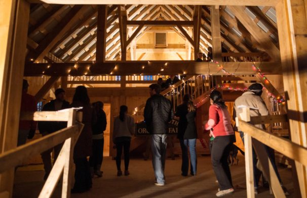 An open house at a newly built post and beam barn; several people stand in an open space under large beams