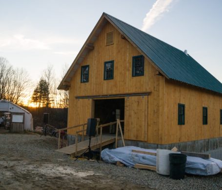 The sun sets behind a handsome timber frame barn