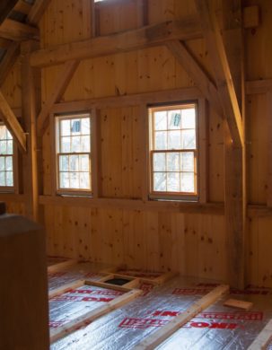 Interior of a timber framed barn as an insulated floor layer is laid down
