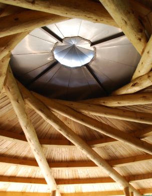 A spiral of rafters come together around a central cupola in this reciprocating timber frame