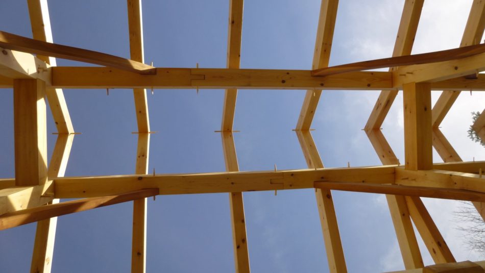 Timber frame rafters against a blue sky