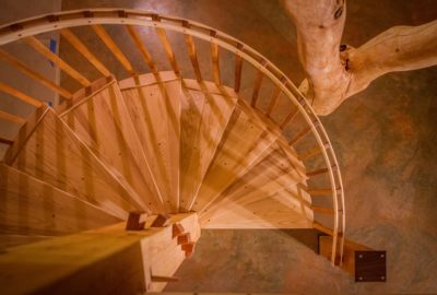 A spiral staircase stands beside a forked post