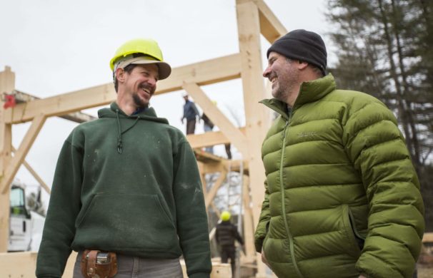 Two men in front of a timber frame raising