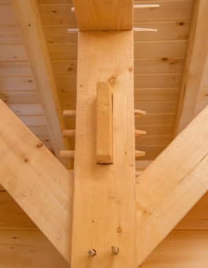 A mortise and tenon joint holds a post and beam together in a timber frame bunkhouse