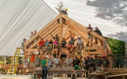 Participants in a timber framing workshop pose on the finished frame