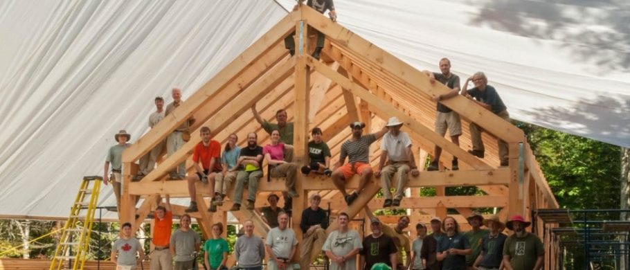 Participants in a timber framing workshop pose on the finished frame