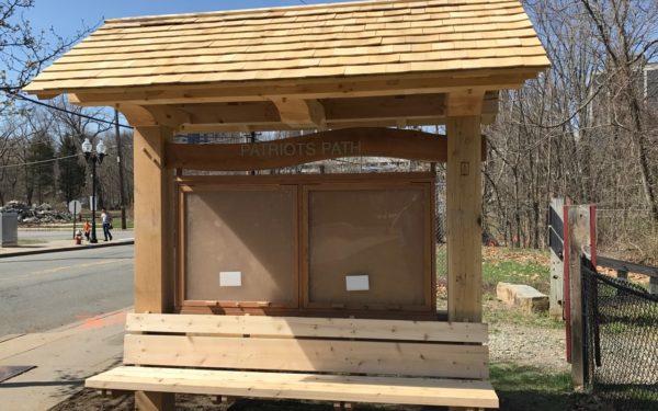 A timber frame kiosk with bench and display area and cedar shingle roof
