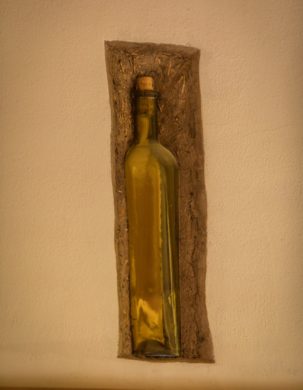 A glass bottle is embedded into a plastered wall