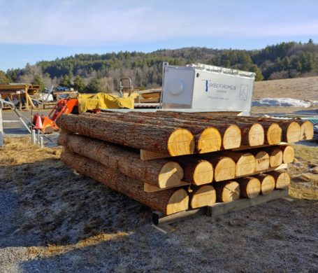 A stack of round log floor joists waiting to be moved into the shop