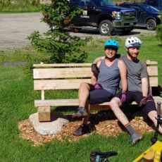 a couple of bikers rest on this park Bench in Vermont