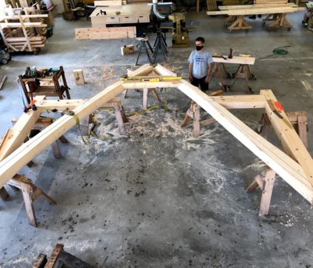 A section of a timber framed home is assembled in a woodworking shop