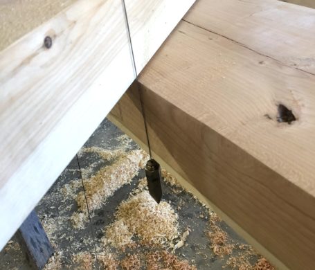 A close up photo of someone setting up a plumb line scribe to fit two timbers together.