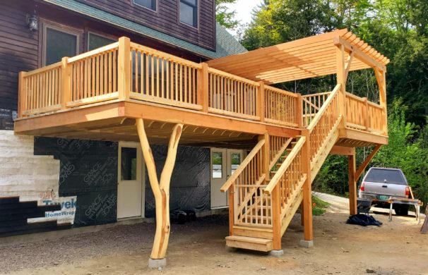 A new timber framed deck, porch, and pergola addition with a forked locust post.