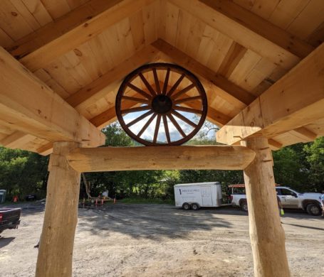 A covered entry made from timber with an inset wagon wheel