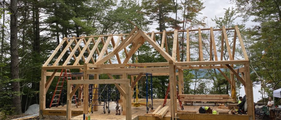 A timber frame cabin is raised in a forested setting in New Hampshire