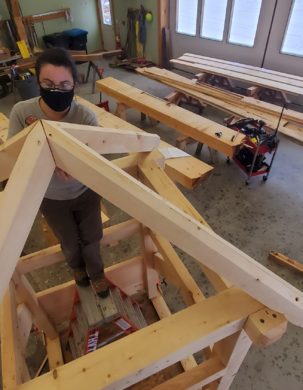 A timber framer installs all four hip rafters, which meet at a single point at the peak of the roof