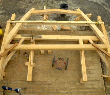 Two rough sawn timber frame bents sit preassembled on the floor deck the morning of the raising