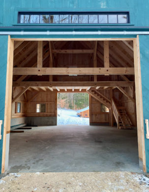 Transom window over sliding doors in timber frame barn