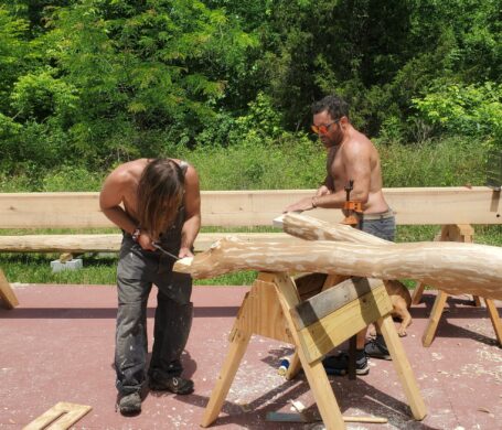 Two people work on a timber