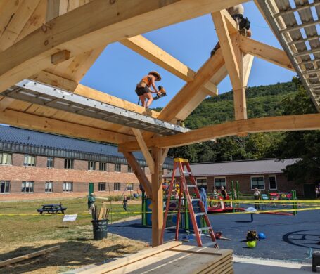 A construction site where a timber frame pavilion is being roofed.