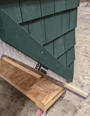 A closeup photo of trim and cedar shingles which have been stained forest green.