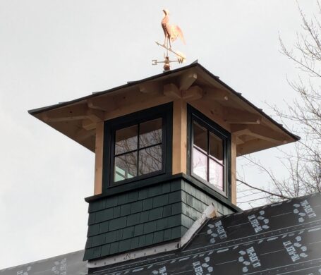 A photos of a timber frame cupola in Waterbury, VT with a Rooster weathervane.