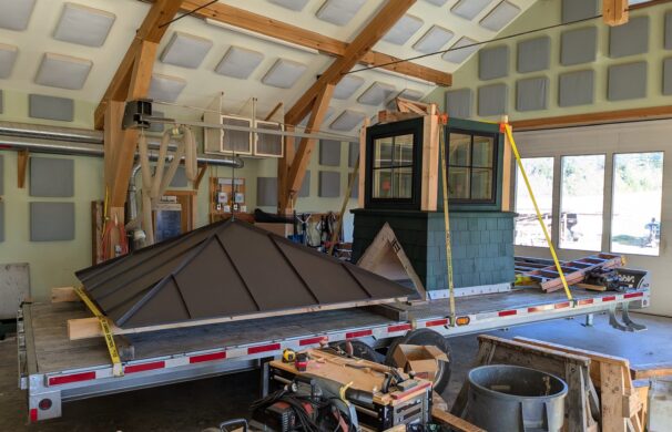 A photo of the inside of a timber framing shop in Montpelier Vermont, with a disassembled cupola strapped down to a flatbed trailer, ready for deliver.