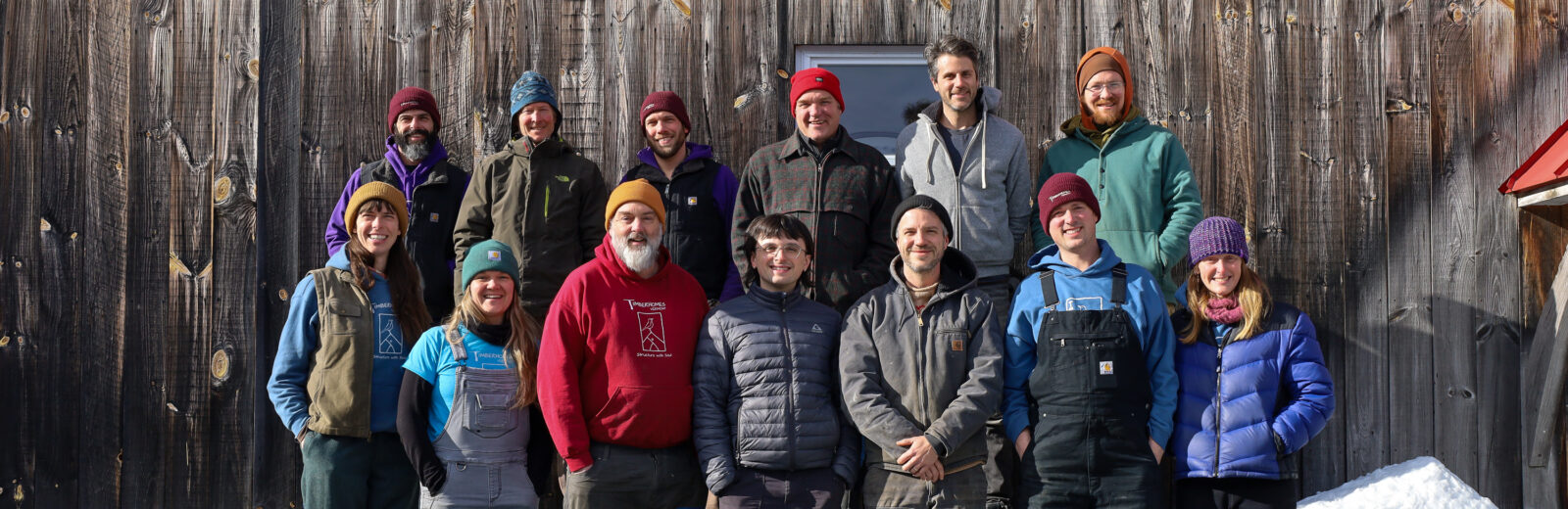 The timber gnomes pose for a company portrait outside their Vershire shop. Everyone is smiling and it's a beautiful bright snowy day