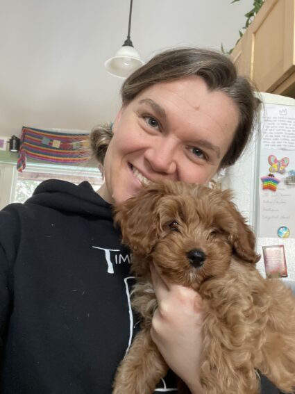 A photo of a timber frame builder, Carly Lagasse, and her small dog.