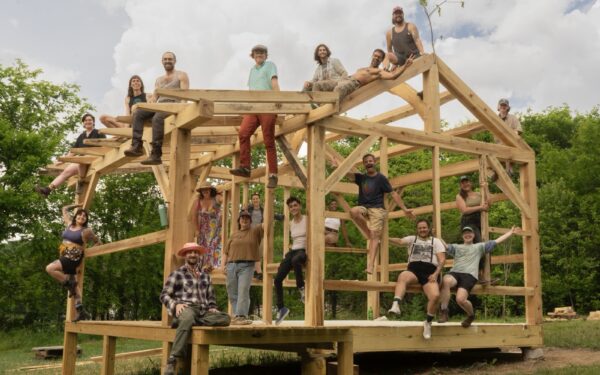 Workshop participants pose on the timber frame structure they built.