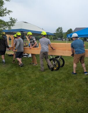 volunteers rolling timbers with a beam cart